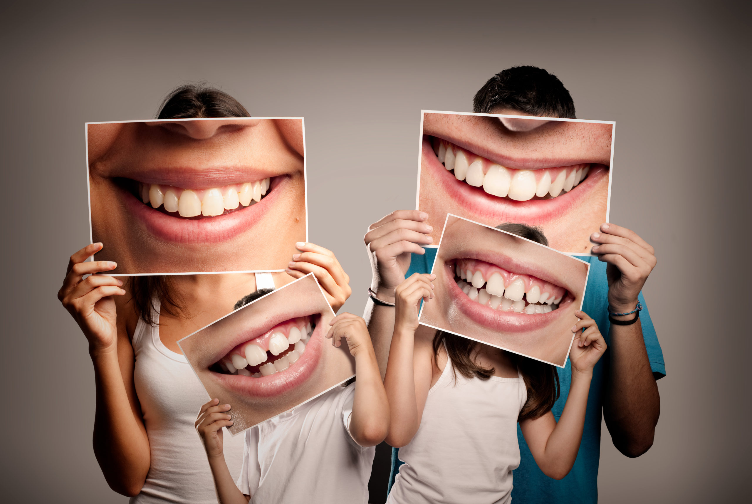 Young Family with Children Holding a Picture of a Mouth Smiling | Solomon Family Dentistry in Summerville & Mount Pleasant, SC